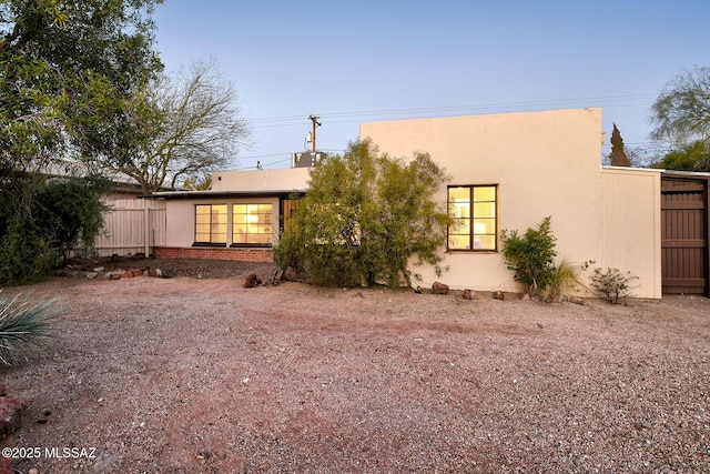 back of property featuring fence and stucco siding