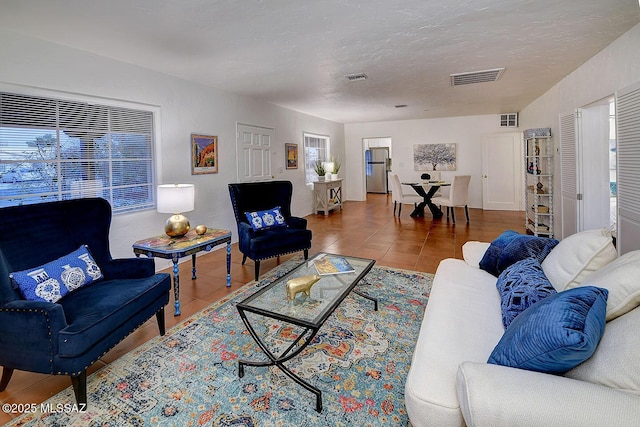 living room featuring tile patterned floors, visible vents, and a textured ceiling