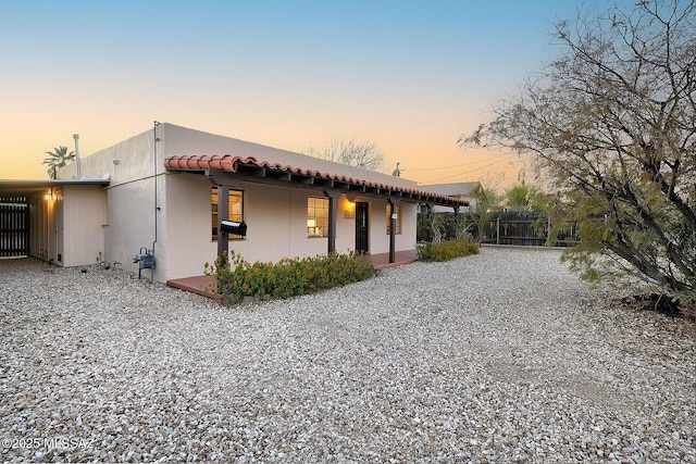 view of front of property with stucco siding, a tiled roof, and fence