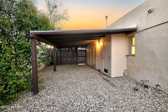 exterior space with an attached carport, gravel driveway, and fence