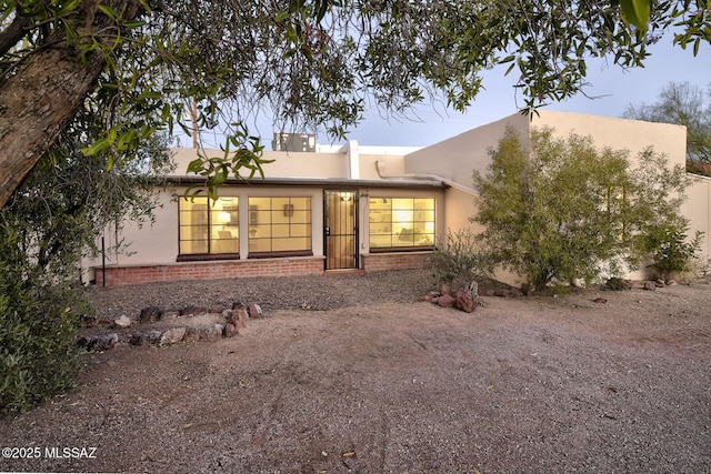 back of house featuring brick siding and stucco siding