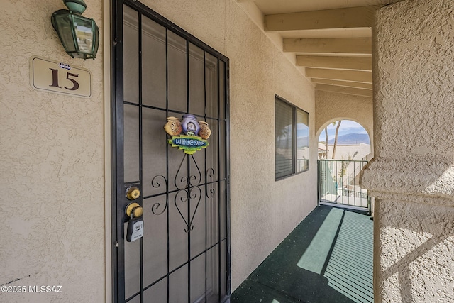 property entrance featuring a balcony and stucco siding