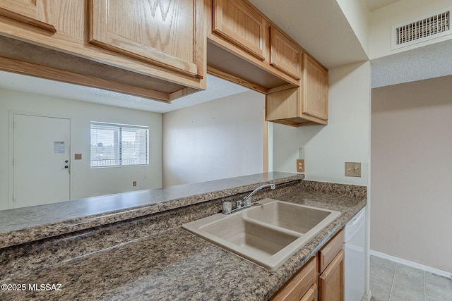 kitchen with light tile patterned floors, baseboards, visible vents, dishwasher, and a sink