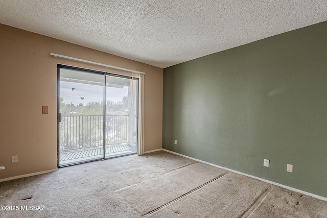 spare room featuring carpet floors, a textured ceiling, and baseboards