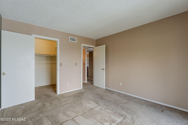 unfurnished bedroom featuring carpet, a closet, visible vents, a spacious closet, and a textured ceiling