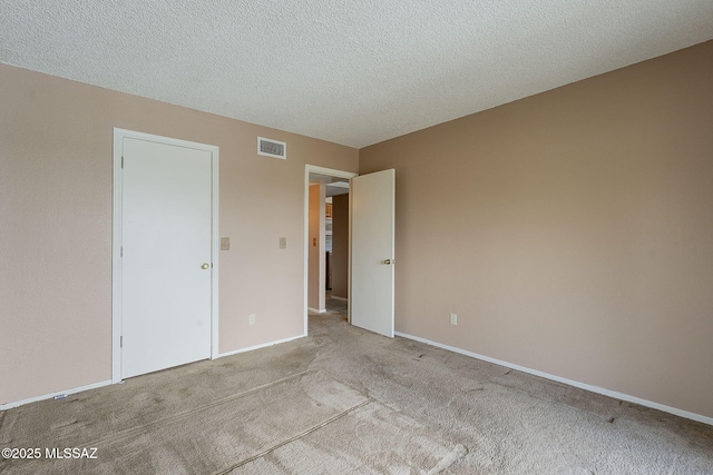 empty room with a textured ceiling, carpet floors, visible vents, and baseboards