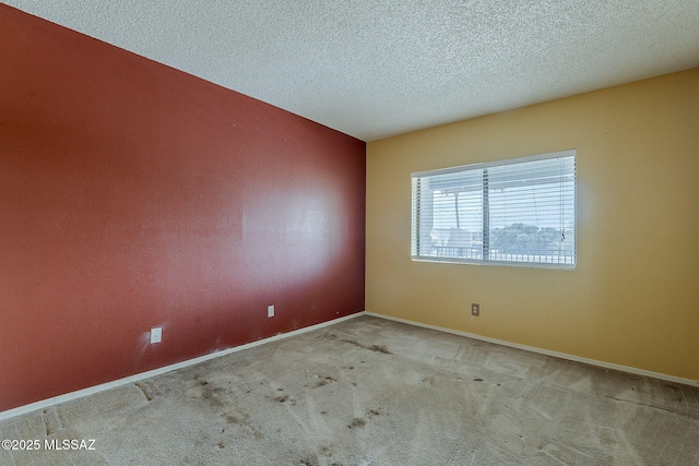 carpeted spare room with baseboards and a textured ceiling