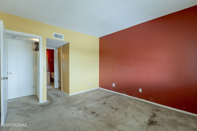 carpeted spare room featuring visible vents, a textured ceiling, and baseboards