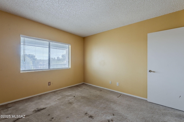 unfurnished room featuring carpet floors, baseboards, and a textured ceiling