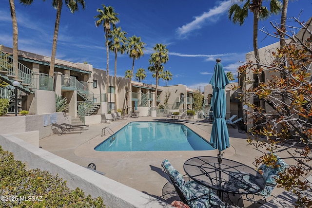 community pool featuring stairway, a patio area, and a residential view