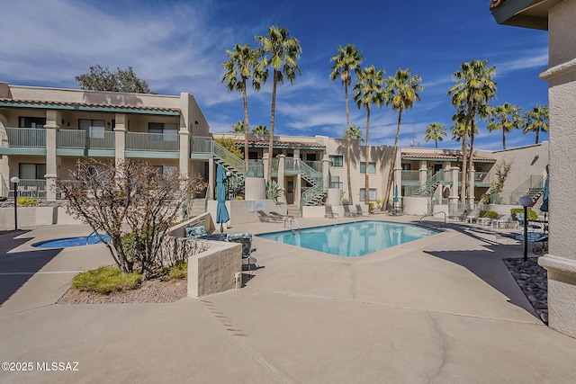 community pool featuring stairway and a patio area