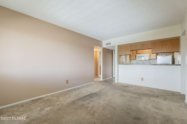 unfurnished living room featuring visible vents, light carpet, a textured ceiling, and baseboards