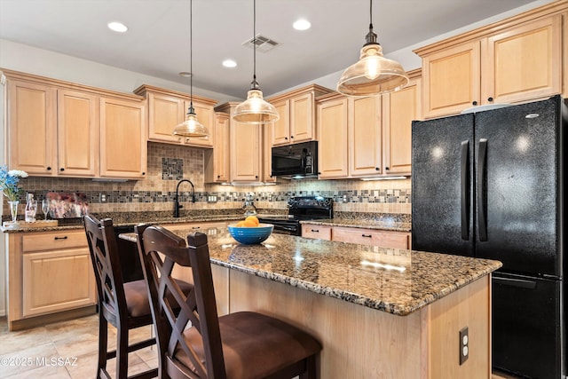 kitchen with black appliances, light brown cabinets, and visible vents