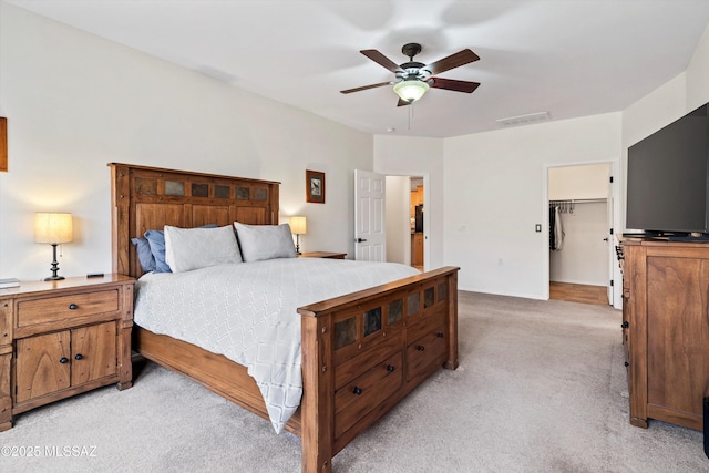 bedroom featuring a ceiling fan, a walk in closet, light carpet, and visible vents