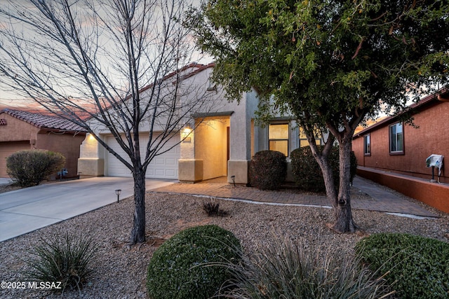 view of front facade featuring driveway, a tiled roof, and stucco siding