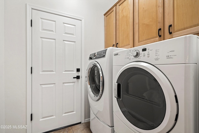 washroom with cabinet space, light tile patterned floors, and washing machine and clothes dryer