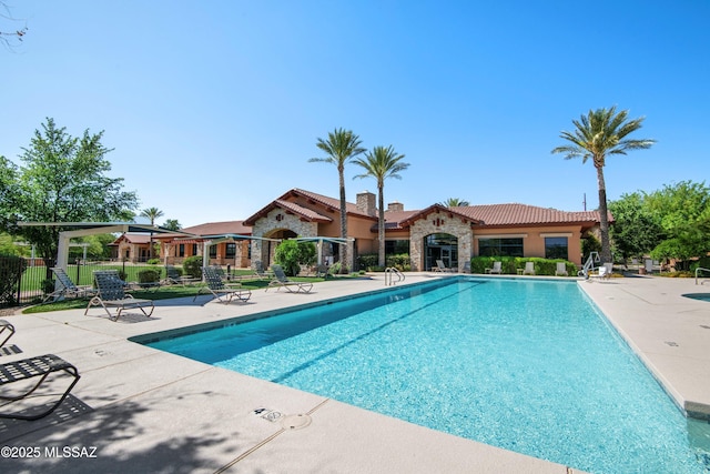 community pool featuring fence and a patio