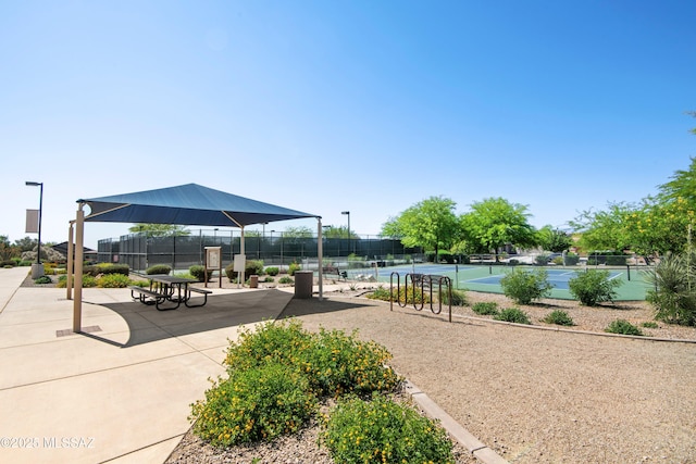 view of property's community with a tennis court and fence