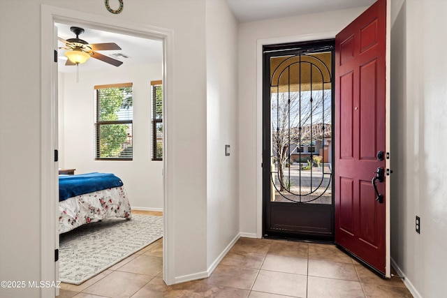 entryway with a ceiling fan, baseboards, and light tile patterned floors