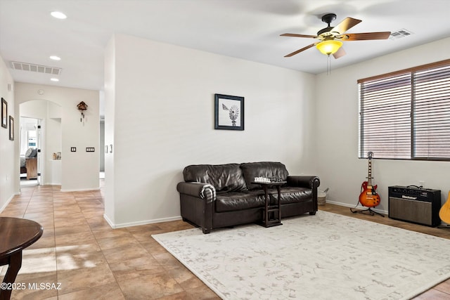 living room with arched walkways, ceiling fan, visible vents, and baseboards