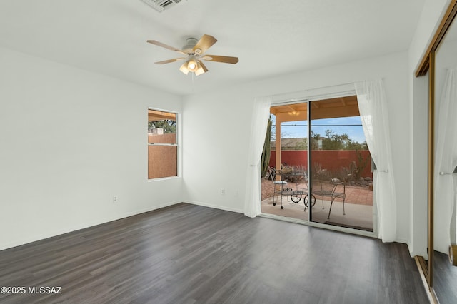 empty room featuring dark wood-type flooring, a wealth of natural light, baseboards, and a ceiling fan