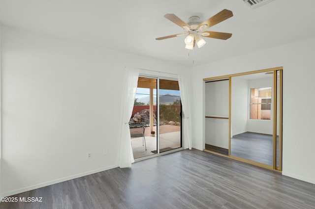 empty room with ceiling fan, visible vents, baseboards, and wood finished floors