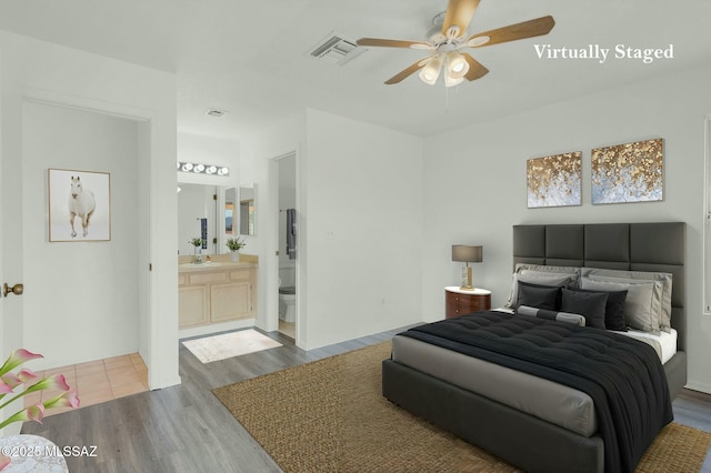 bedroom featuring ceiling fan, connected bathroom, a sink, wood finished floors, and visible vents