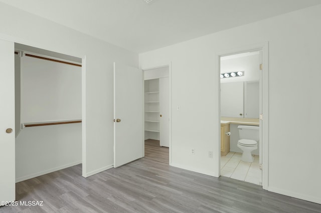 unfurnished bedroom featuring a closet, connected bathroom, and wood finished floors