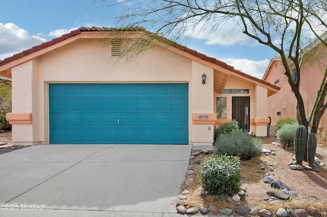 view of front of house with concrete driveway, a tiled roof, an attached garage, and stucco siding