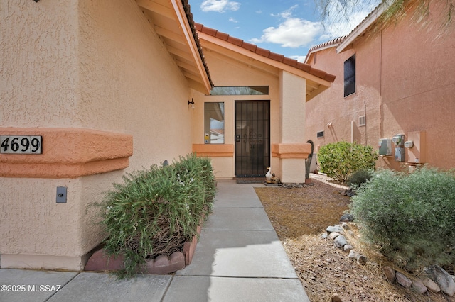 entrance to property featuring a tiled roof and stucco siding