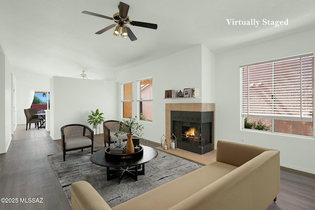 living area featuring ceiling fan, wood finished floors, a multi sided fireplace, and baseboards