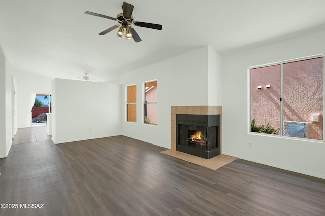 unfurnished living room featuring wood finished floors, a multi sided fireplace, and baseboards