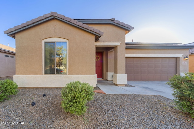 view of front of property featuring a garage, driveway, a tile roof, and stucco siding