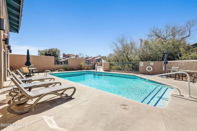 community pool with a patio area and fence