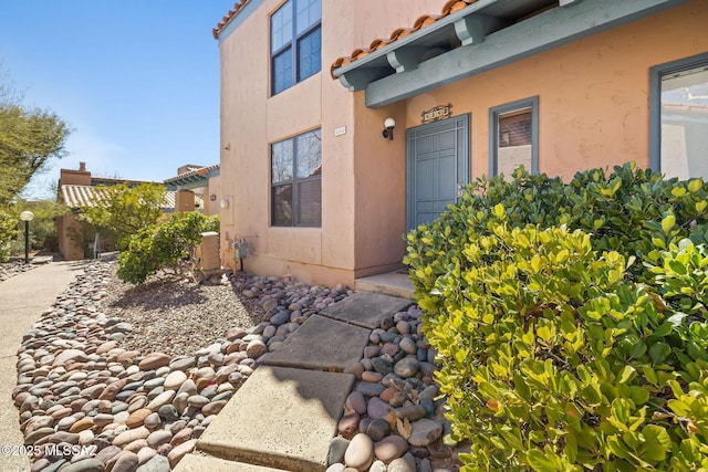 view of exterior entry featuring stucco siding and a tiled roof