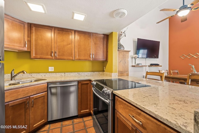 kitchen featuring a sink, stainless steel appliances, light stone counters, and brown cabinets