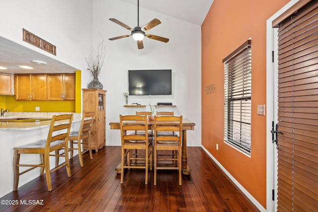 dining area featuring visible vents, dark wood-type flooring, baseboards, ceiling fan, and a towering ceiling