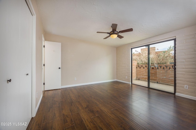 unfurnished room featuring wood-type flooring, baseboards, a textured ceiling, and brick wall