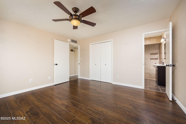 unfurnished bedroom with dark wood-style floors, visible vents, and baseboards