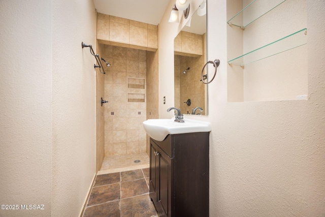 full bathroom with a tile shower and vanity