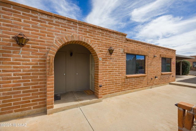 property entrance featuring a patio area and brick siding