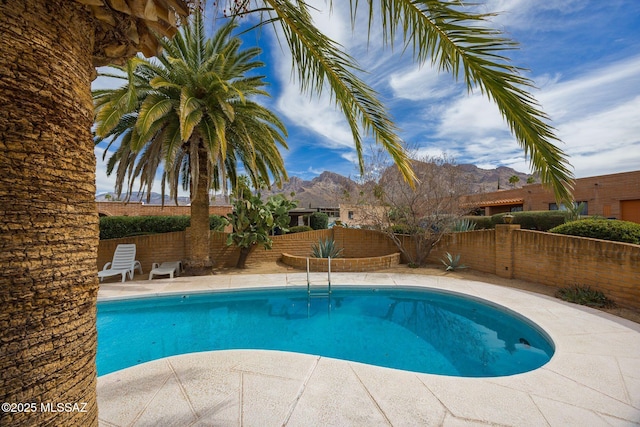 view of pool with a fenced in pool, a fenced backyard, a mountain view, and a patio