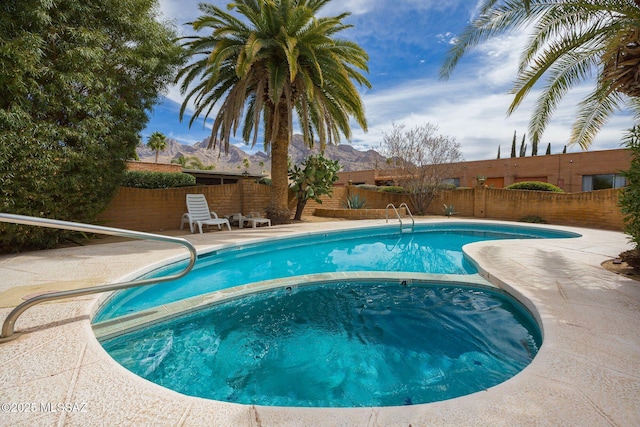 view of pool featuring a fenced backyard, a mountain view, an in ground hot tub, a fenced in pool, and a patio area