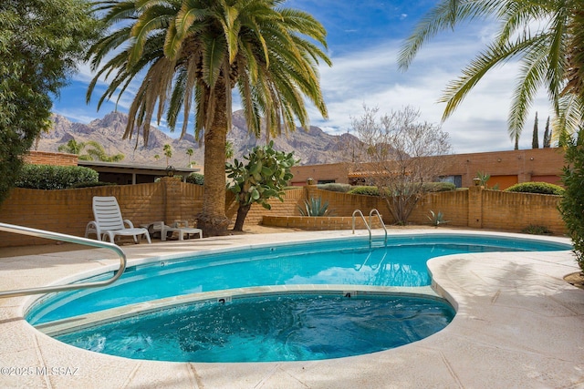 view of swimming pool with a fenced backyard, a mountain view, a fenced in pool, and an in ground hot tub