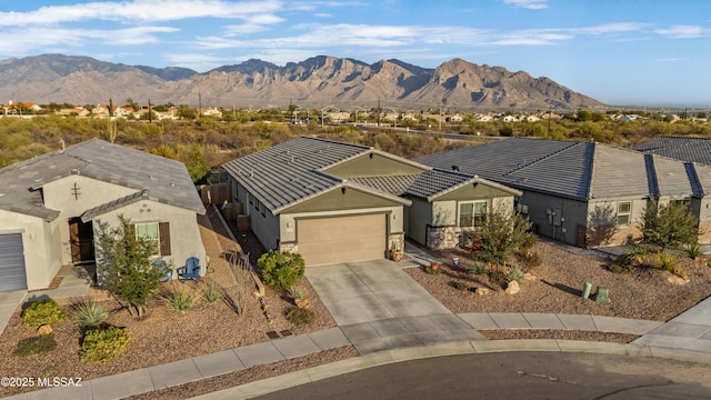 ranch-style home featuring a garage, concrete driveway, a mountain view, and stucco siding