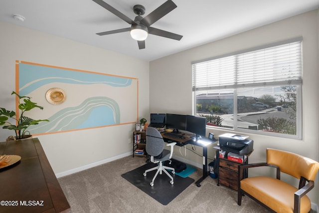 carpeted office space with a ceiling fan and baseboards