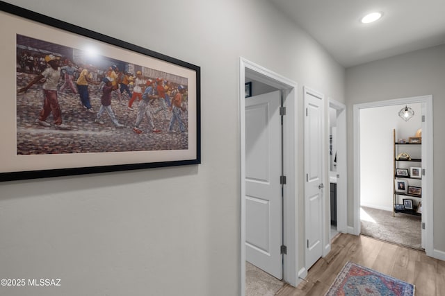 hallway featuring light wood-type flooring, baseboards, and recessed lighting