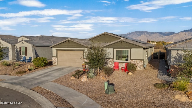 view of front of home with a garage, driveway, stone siding, a mountain view, and stucco siding