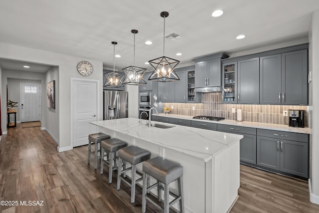 kitchen featuring stainless steel appliances, gray cabinets, visible vents, dark wood-type flooring, and a sink