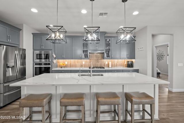 kitchen with tasteful backsplash, visible vents, stainless steel appliances, and gray cabinetry